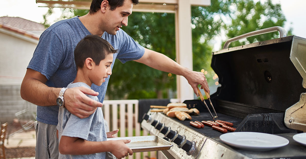 father and son using an outdoor grill