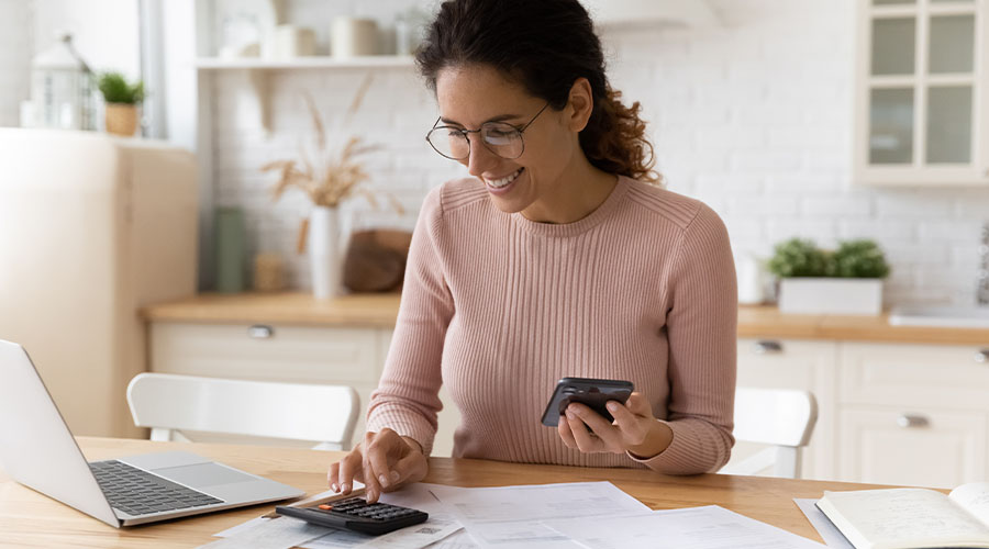 woman smiling while typing calculator